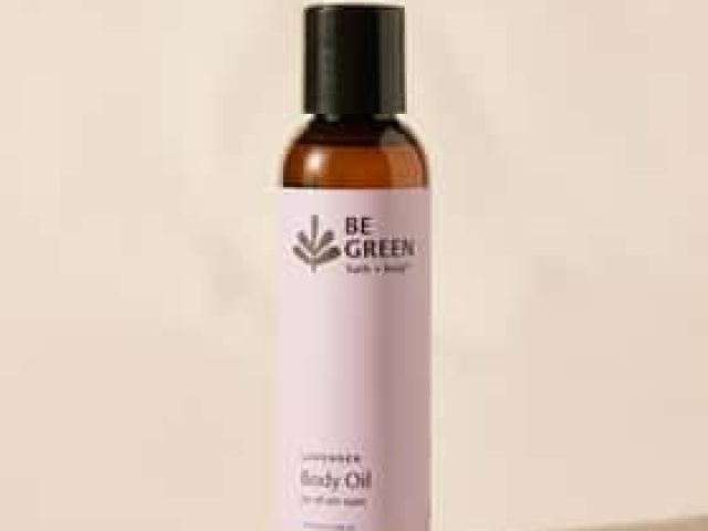 Photograph of amber Be Green lavender body oil bottle with black cap on beige background