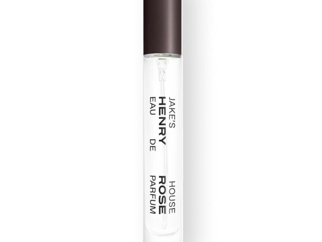 Photograph — clear glass perfume roller vial with dark cap and vertical black label text