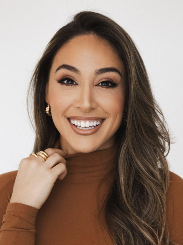 Photograph — smiling woman with long brown hair in rust turtleneck and gold earrings