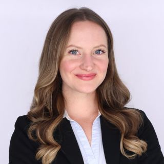 Photograph of smiling professional woman with wavy brown-blonde hair, black blazer