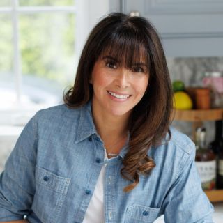 Photograph: smiling woman with bangs in denim shirt in bright kitchen