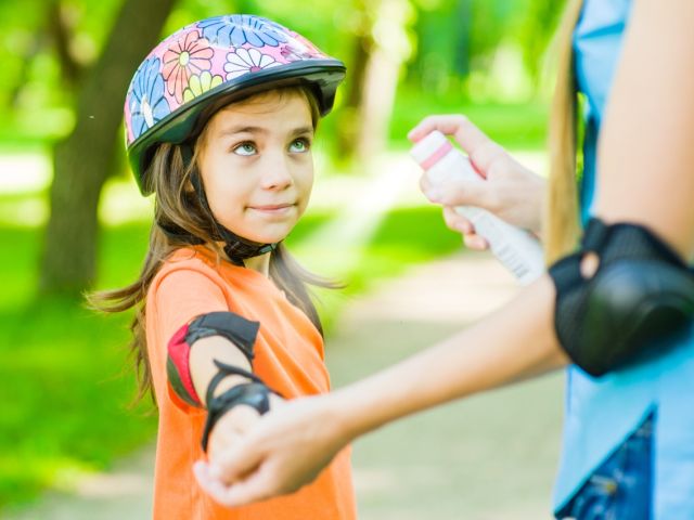 Child being sprayed with sunscreen