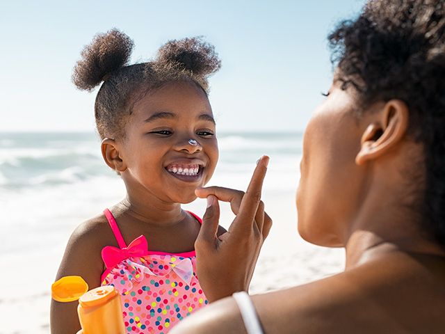 A mother putting sunscreen on her daughter