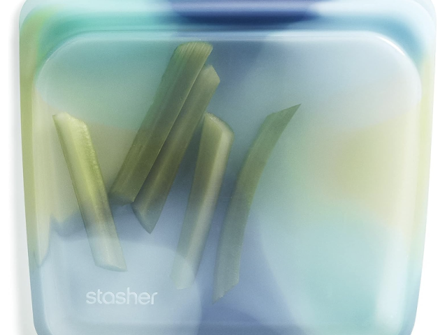 Translucent silicone bag containing green vegetable sticks, on a light background.
