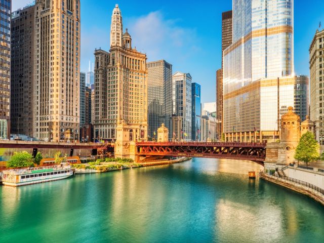 Chicago skyline with colorful buildings, a bridge, and a river under a clear blue sky.