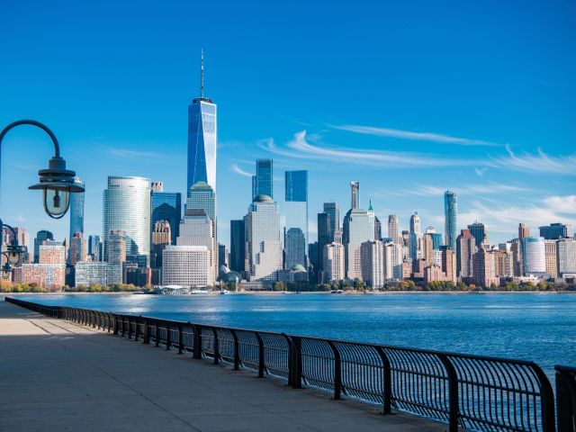 Skyline of New York City with skyscrapers, waterfront, and clear blue sky.