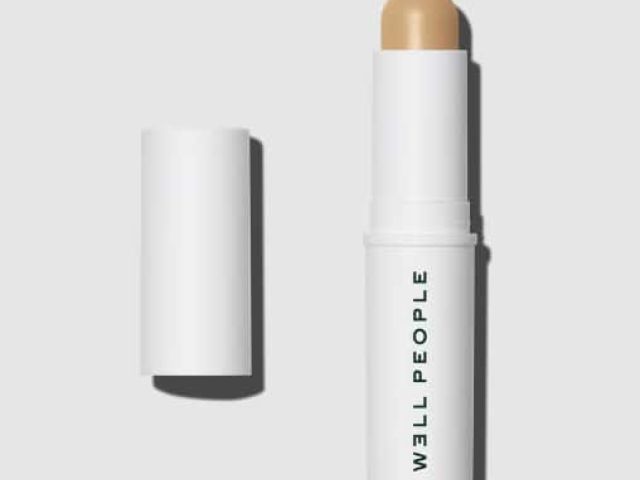 Creamy stick foundation in a white tube, cap removed, on a light gray background.