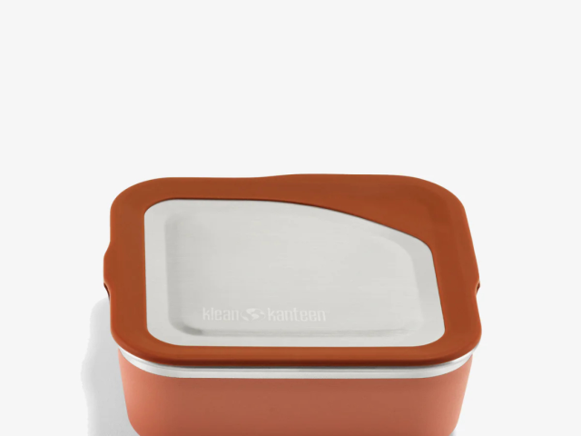 Square food storage container with an orange base and a white lid.