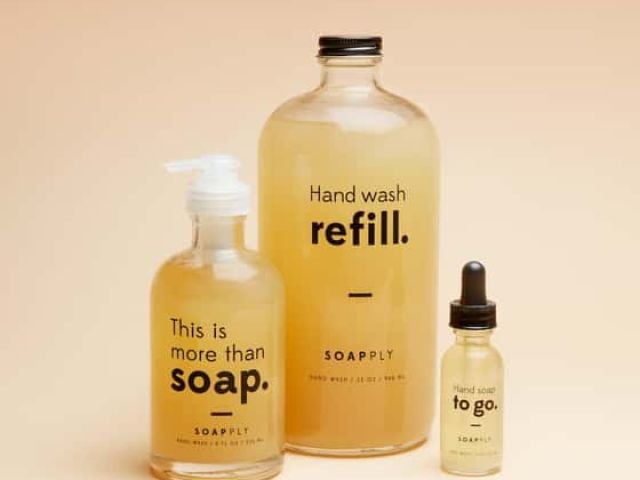 Three bottles of liquid soap in varying sizes with minimalist labels on a soft background.