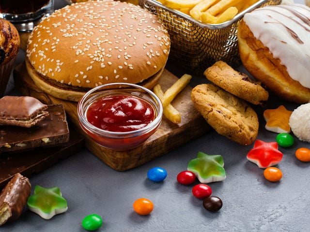 A variety of fast foods and snacks, including a burger, fries, candies, and desserts.