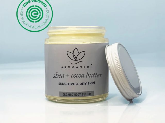 Jar of organic body butter labeled "shea + cocoa butter" with a silver lid.