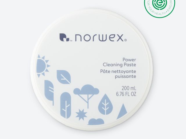 Round container of Norwex Power Cleaning Paste with light blue design elements and a green certification logo.