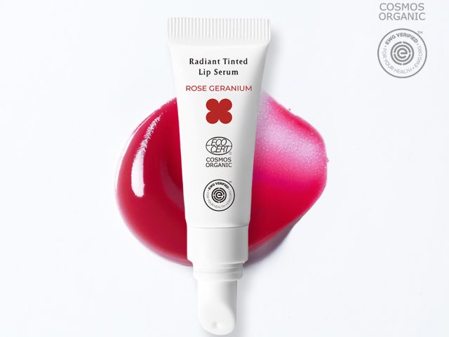 White tube of lip serum with pink gel stain on a white background.