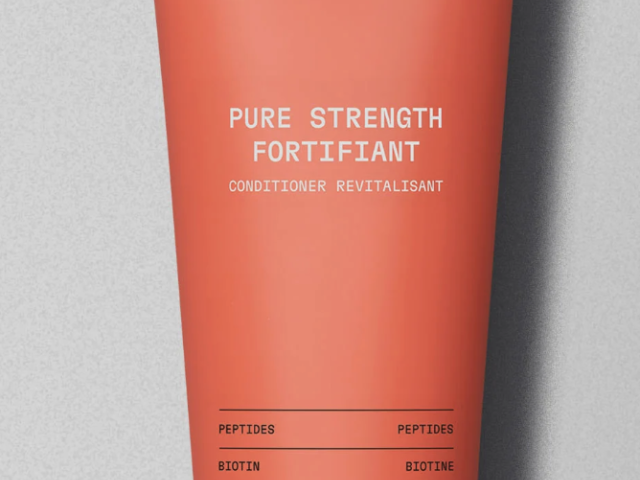 Photograph: coral Clean Journey conditioner tube with white logo and black cap on gray background