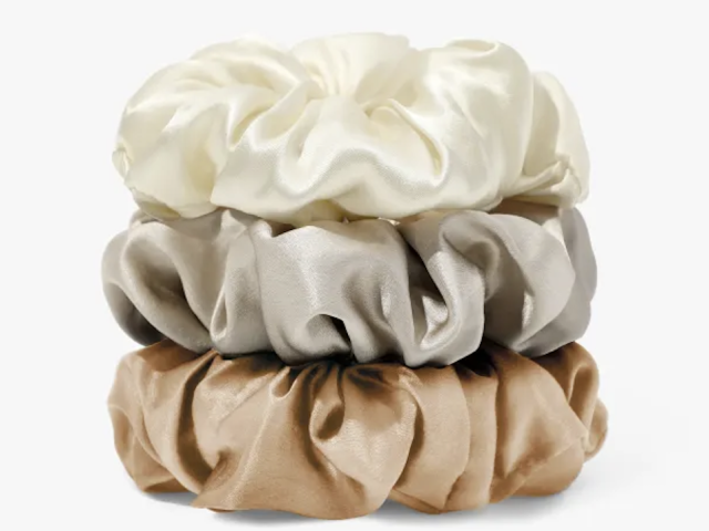 Photo of three satin hair scrunchies stacked: ivory, silver-gray, warm tan