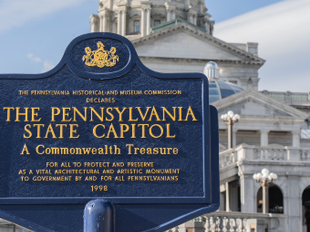 Photograph: blue Pennsylvania State Capitol historical marker with gold text, capitol dome behind