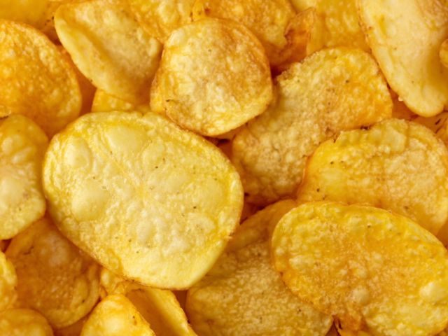 Close-up photograph of golden, salted potato chips