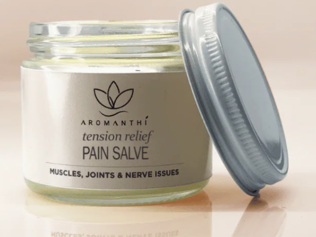 Photograph: open glass jar of Aromanthi tension-relief pain salve, lid leaning