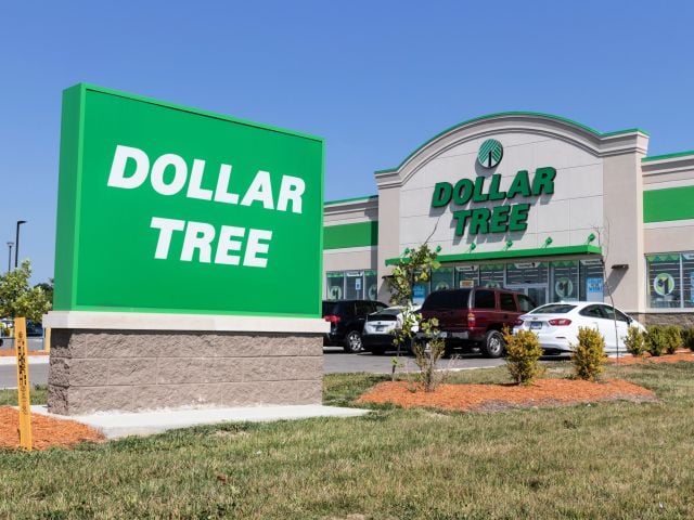 Photograph of Dollar Tree storefront with large green sign and parked cars