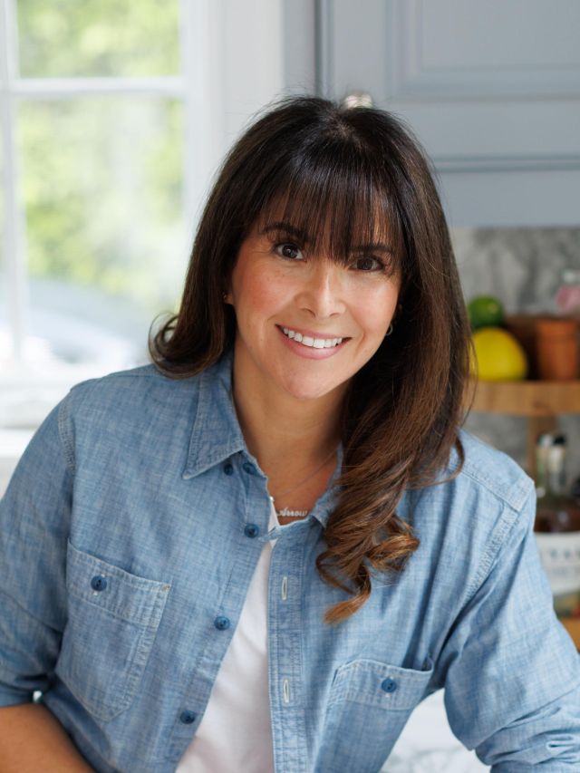 Photograph: smiling woman with bangs in denim shirt in bright kitchen