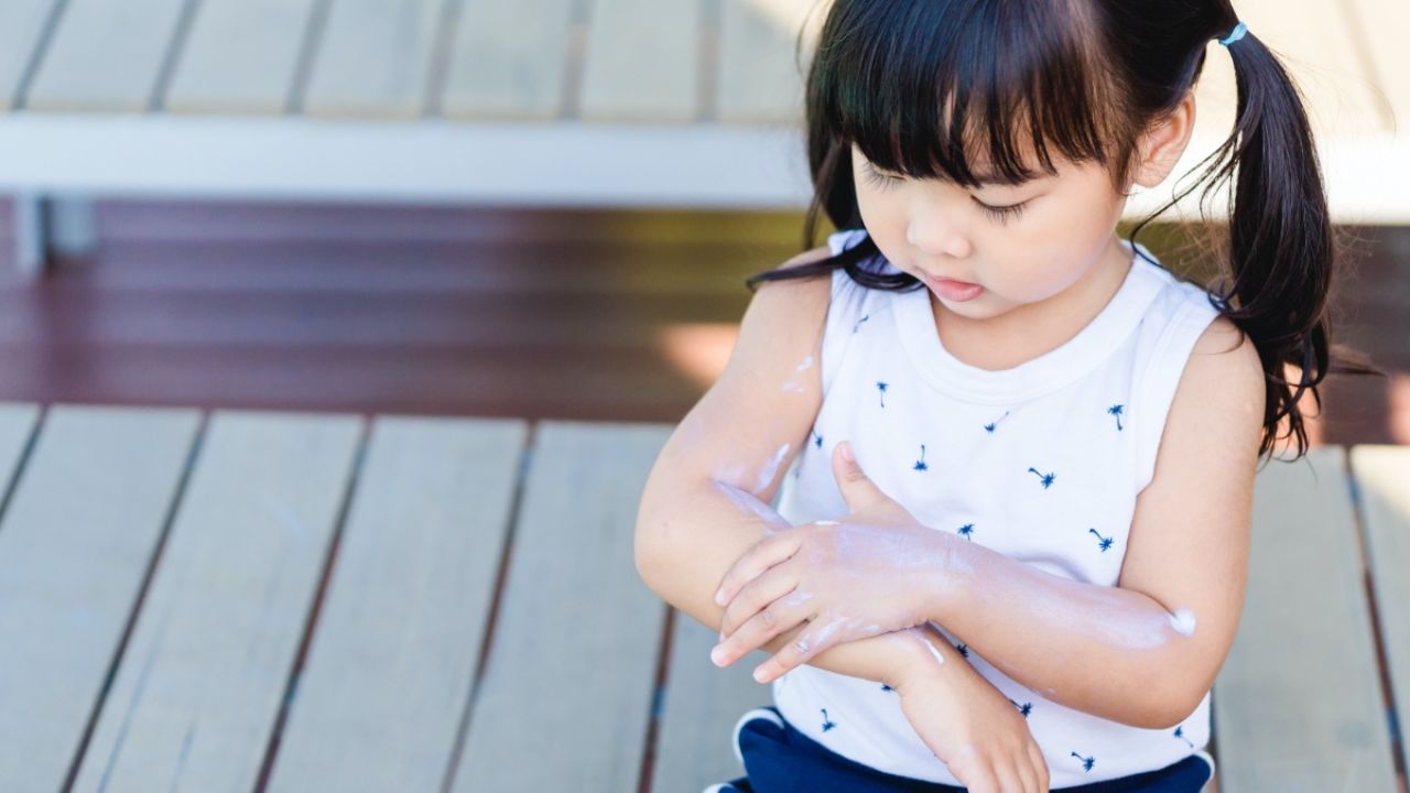 Child applying sunscreen
