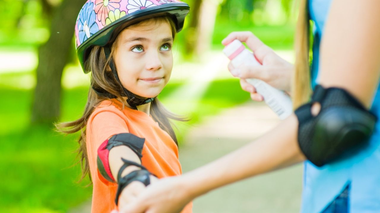 Child being sprayed with sunscreen