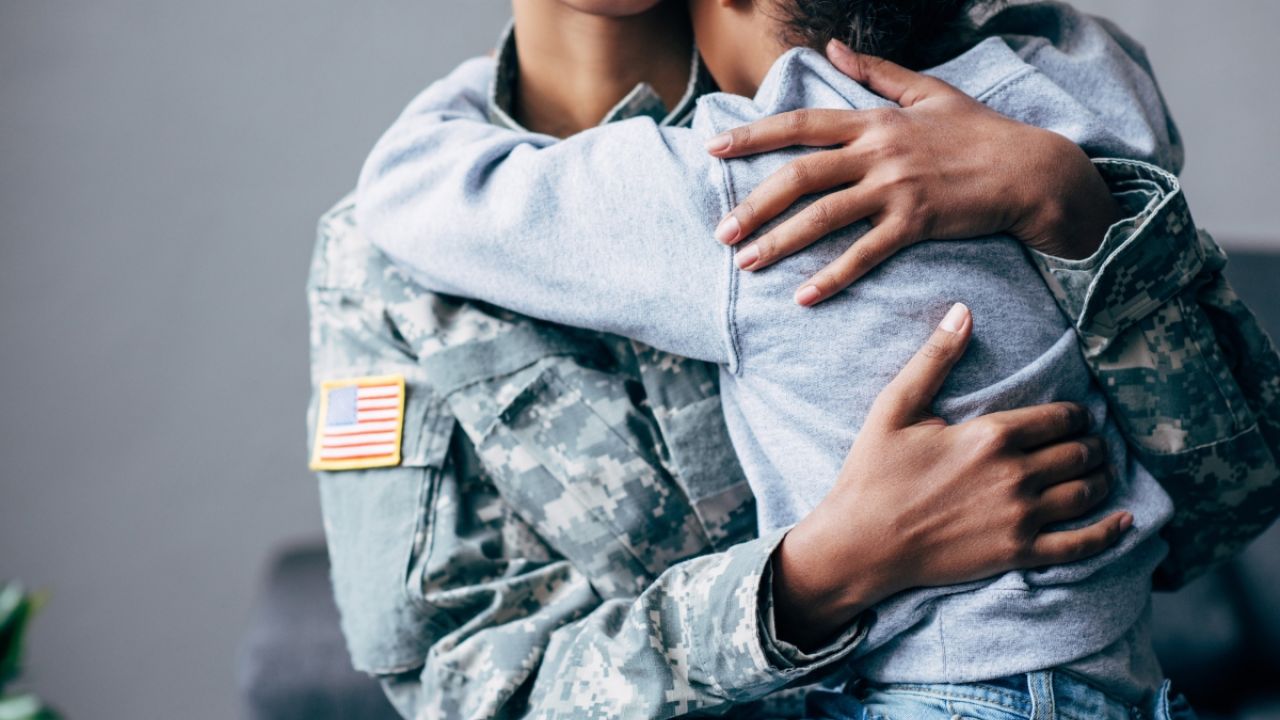 Child hugging parent in military fatigues 