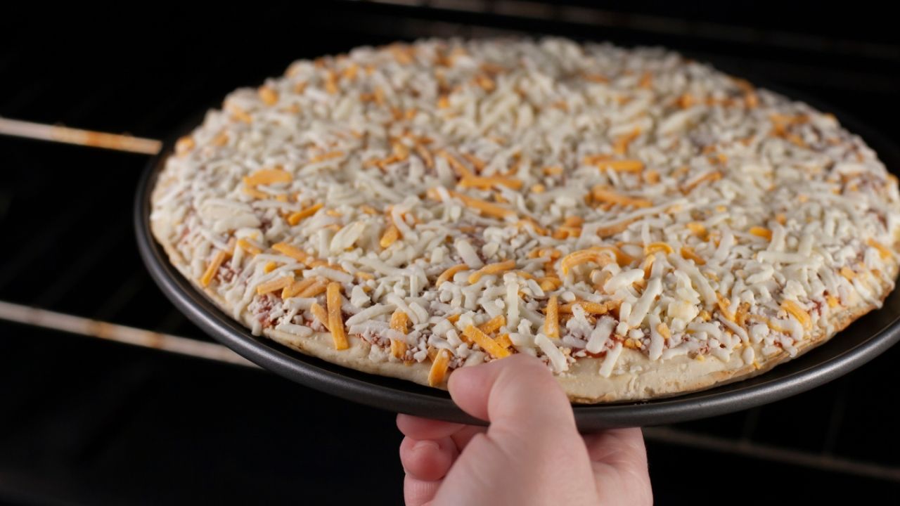 Person putting frozen pizza in oven