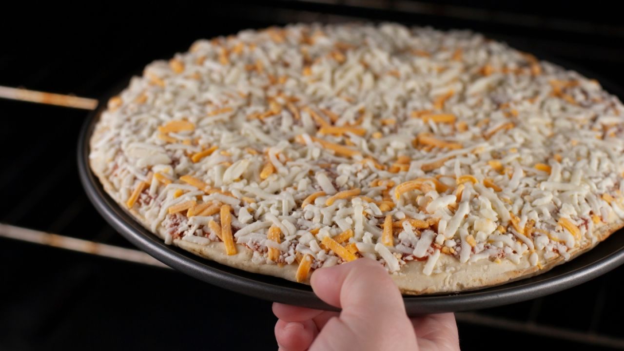 Person putting frozen pizza in oven