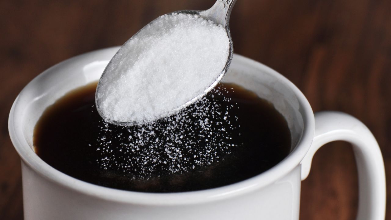 Person putting sweetner into coffee