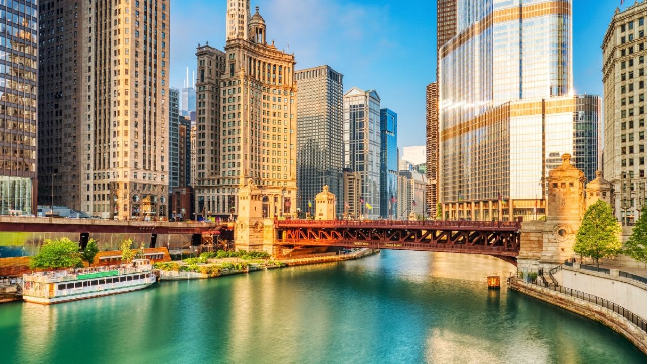 Chicago skyline with colorful buildings, a bridge, and a river under a clear blue sky.