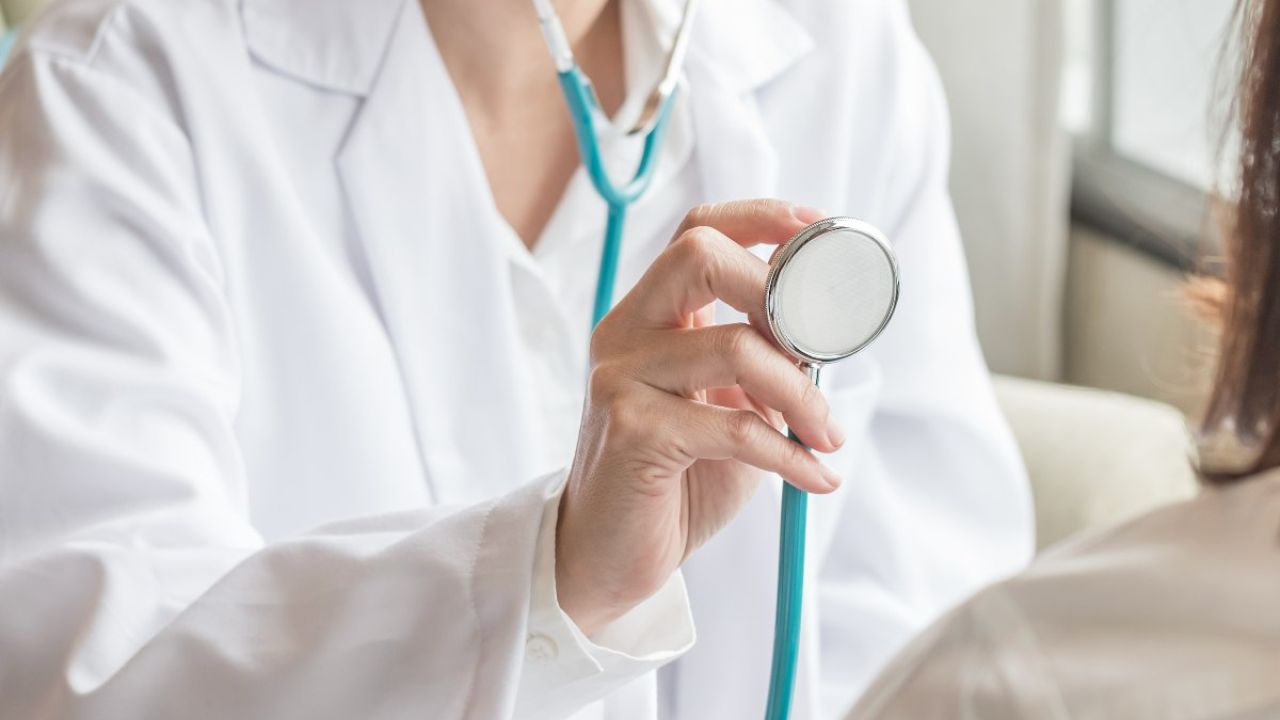 A healthcare professional holds a stethoscope, preparing to examine a patient.