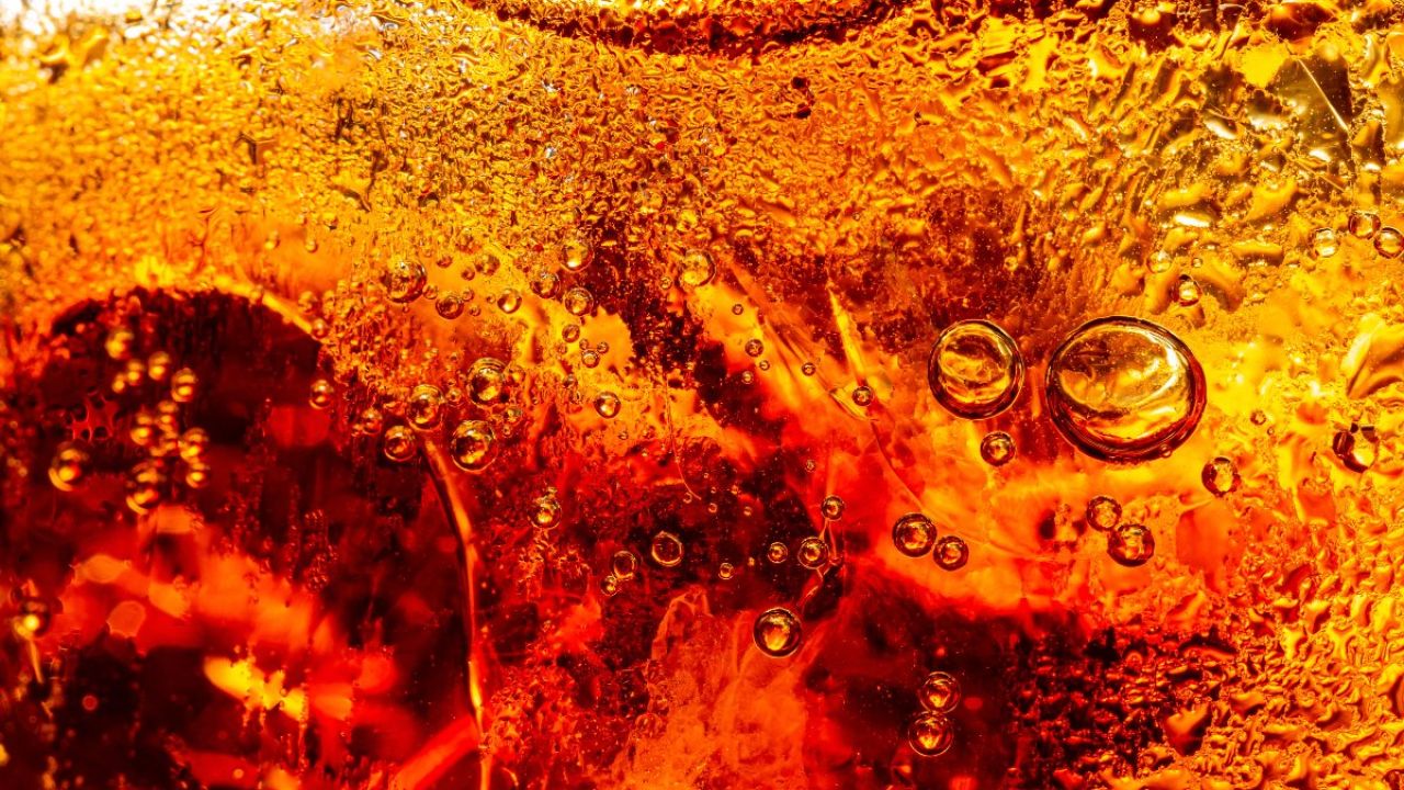 Macro photograph of amber liquid with suspended bubbles and textured surface
