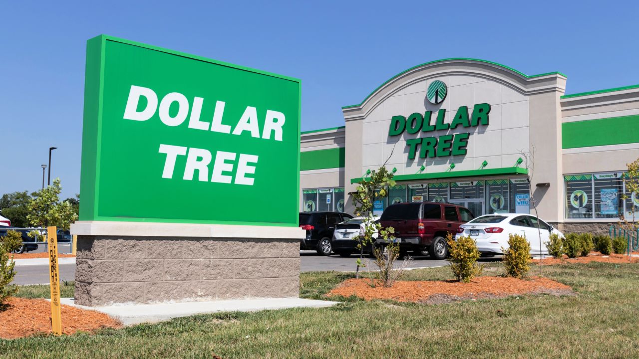 Photograph of Dollar Tree storefront with large green sign and parked cars